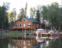 View of cabin from lake with boats